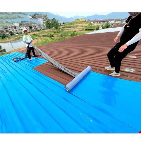 Two workers applying Real Deal Self Adhesive Roofing Felt Roll With Aluminum Foil Backing on a roof.