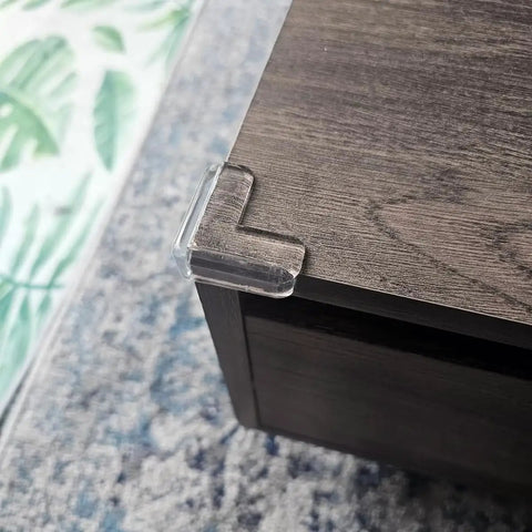 Clear corner protector installed on wood, part of 12 pack, food-grade silicone, for baby proofing edges, tables, safe kid proofing bumpers.