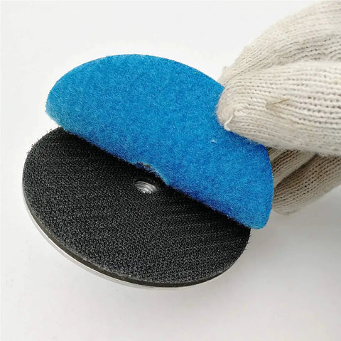 Gloved hand holding Aluminum Backer Pad Set 4 Inch Hook and Loop Backing Pads 5/8-11 Arbor, highlighting Velcro attachment