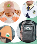 58mm round button badge worn on peach hat; green smiley face design
58mm round button badge pinned to a school sweater; white with crest
58mm round button badge on orange beanie; white background with green dinosaur
58mm round button badge attached to gray backpack; Christmas tree design