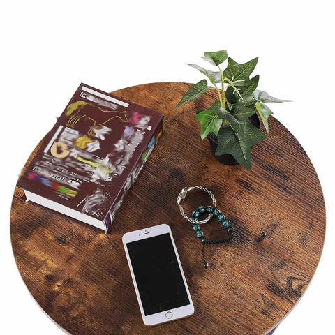 Round Two Tier Side Table With Open Storage Shelf, Anti Scratch Protective Pads, Kid Safe Curved Edges, Straight Up Sturdy Metal End Table For Cozy Living Rooms And Bedrooms, featuring books, phone, and plant on rustic brown surface.
