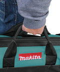 Person carrying Makita 20 Inch Contractor Tool Bag Built For The Job Site With Heavy Duty Zippers Reinforced Handles And Industrial Fabric