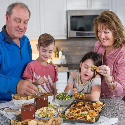 Family enjoying chips and dips in a modern kitchen setting, featuring a rustic wooden countertop and warm lighting.