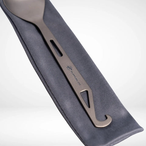 Ultralight Titanium Spork For Backpacking And Camping Reusable Travel Utensil And EDC Spork With Multi Function Hook Featherweight At 0.51 Oz Durable Yet Flexible For Ultra Lightweight Gear against fabric case