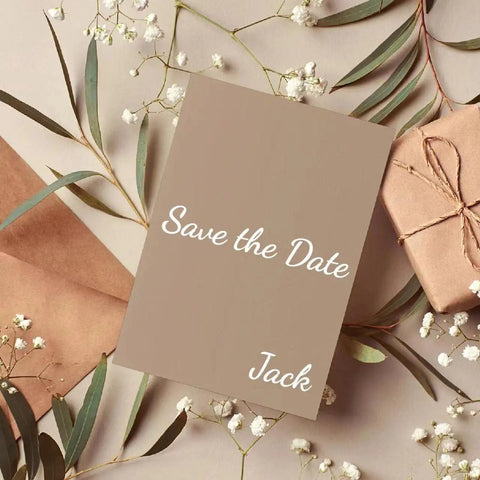 Save the date card with name Jack on beige paper, surrounded by envelopes and flowers.