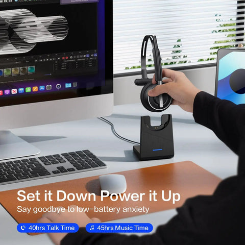 Wireless Headset With Microphone For PC And Phone, V5.2 Noise Cancelling Mic on charging base beside computer monitor