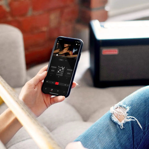 Person using mobile app with Spark 40-Watt Combo Practice Amp for Electric Guitar, Bass, and Acoustic visible in background