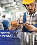 Male factory worker in yellow hard hat and blue overalls inspecting metal parts with calipers