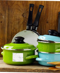 Green and blue cooking pots with black handles on a wooden kitchen counter, ideal for kitchenware display.