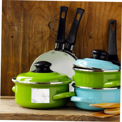 Green and blue cooking pots with black handles on a wooden kitchen counter, ideal for kitchenware display.