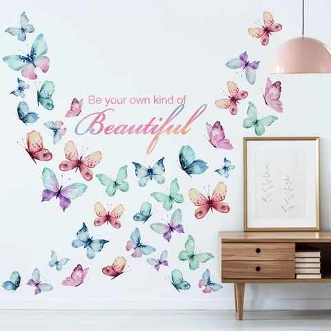 Black Girl Magic Wall Decals You Are Beautiful Inspirational Stickers with colorful butterflies and 'Be your own kind of Beautiful' text on a white wall next to a lamp and table. Afro Butterfly Design and Positive Religious Sayings Dope Vibe.