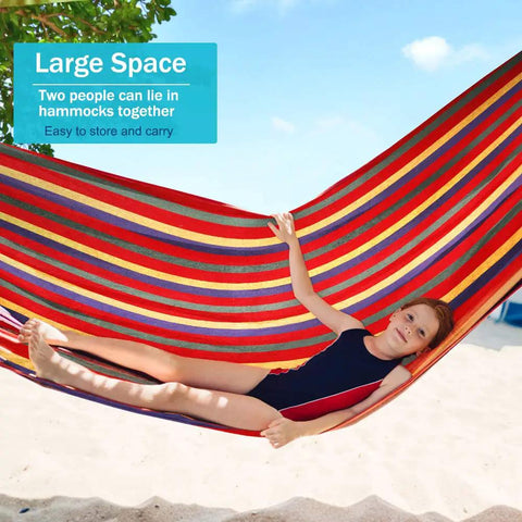 Child relaxing in Heavy Duty Canvas Camping Hammock With Thick 320G Fabric, 550Lb Load, colorful stripes at beach