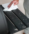 Close-up of Crocodile Cloth Grill wipe used on a black metal grill grate; white pre-moistened cloth.