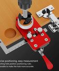 Stainless Steel Hinge Drilling Jig For 35mm Cup Hinges With Ball Bearing Guide shown positioned on a wooden cabinet for precise drilling.