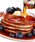 Stack of pancakes with blueberries and maple syrup being poured, representing use for Maple Syrup Filters Set 7 Piece Kit.