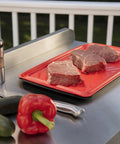 Red tray for raw meat on grill with vegetables, part of Grilling Prep And Serve Trays Set 17 x 10.5 Inch Dual Nesting Trays Red For Raw Meat And Black For Cooked Food Dishwasher Safe BPA Free Safe Food Handling Fits Up To 6 Burgers Perfect BBQ Accessories.