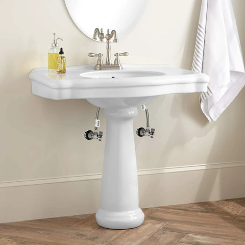 White pedestal sink with two shut-off valve sets installed underneath, showcasing the Two Pack Angle Shut Off Valve Set With One Half Inch Inlet.