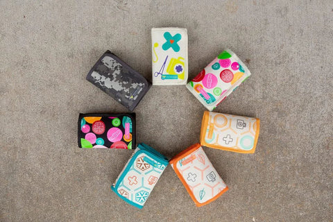PreparaKit kid travel first-aid pouch set, 7 colorful fabric pouches arranged in a circle.
