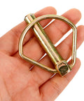 Heavy Duty Linch Pin Lock Shaft Fastener Secures Tractor Trailer Axles With Reliable Spring Loaded Action Made From Durable Carbon Steel And Golden Finish For Industrial Jobs And Heavy Work held in hand.