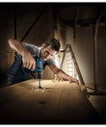 Compact Cordless Drill Driver 12 Volt With Sweet 30 Nm Kickass Torque And Slick 1300 Rpm Motor For Hardcore Handyman Duties And Smooth Home Repair Work used by a handyman drilling into wood.