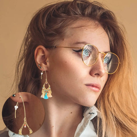 Woman wearing glasses with a gold-colored earring made from 40Pcs Stainless Steel Earring Hooks Hypoallergenic V Shaped Ear Wires And 40Pcs Clear Bullet Earring Backs For DIY Dangle Earrings Jewelry Making Two Color Set Replacement Kit Must Have.