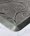 Close-up of ergonomic anti-fatigue floor mat with subtle floral design, part of the Bella Collection, polyurethane, water-resistant, USA-made.