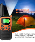 Long Range Walkie Talkies For Adults 2 Pack With 22 FRS Channels 99 CTCSS Privacy Tones VOX LCD Display And LED Flashlight For Hiking Camping And Family Backcountry Adventures Orange with LED flashlight and LCD screen next to an illuminated tent at night outdoors.
