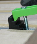 Get Your Work Locked Down Tight With These 10 Pcs 4 Step Clamp Blocks Perfect As CNC Spacer For Hold Down Clamps Super Durable And Precision 3D Printed Gear You Need To Crush Any Project. Close-up of black clamp block secured with green clamp on worktable.