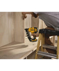 Person using 20V Cordless Angled 16 Gauge Finish Nailer Tool Only, Brushless Motor on wooden cabinet trim
