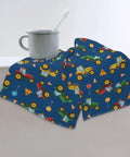 Children's blue towel with vehicle pattern draped on edge, next to white mug with toothbrush.