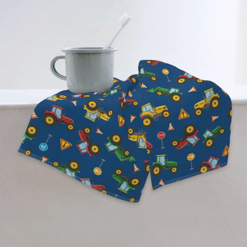 Children's blue towel with vehicle pattern draped on edge, next to white mug with toothbrush.