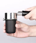 Hands holding 53.3mm portafilter dosing cup in 304 stainless steel with matte black nonstick finish, easy grinder to portafilter transfer