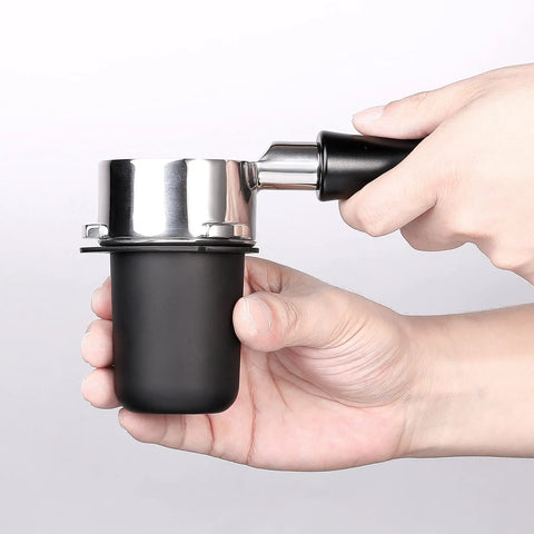 Hands holding 53.3mm portafilter dosing cup in 304 stainless steel with matte black nonstick finish, easy grinder to portafilter transfer