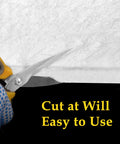 Ceramic fiber blanket insulation, white, being cut with yellow-handled scissors by a gloved hand.