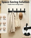 Badass Heavy Duty Wall Hooks Slick Black Metal Coat Hanger And Towel Rack with coats, hats, and bags organized on a wall.