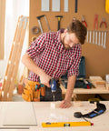 Basswood sheets for crafts on workbench; man in plaid shirt drills a wooden block.