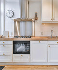 Antique Brass Round Cabinet Knobs 6 Pack installed on white kitchen cabinets with wooden countertop, modern kitchen decor.