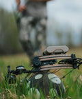 Ultra Portable 9 Inch Sand Filled Archery Target With Carry Handle For On The Go Practice Self Balancing Core Keeps Target Upright After Every Shot Broadhead And Field Point Compatible Great For Backcountry Or Backyard Practice Made In USA in grassy field with bow in foreground