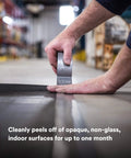 Person using Heavy Duty Duct Tape, Silver, 1 Pack, 1.88 in x 60 yd x 9.0 mil, on warehouse floor for sealing.