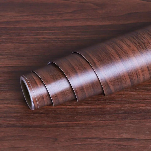 Slick Peel And Stick Countertop Wrap Featuring Sweet Dark Walnut Wood Grain Waterproof Self Adhesive Vinyl roll on wooden surface.