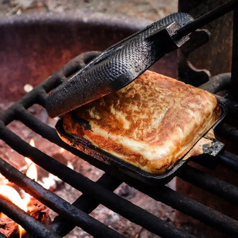 Cast Iron Camp Pie Cooker Set Of 2 for campfire sandwiches on grill, open hinge showing toasted sandwich, pre-seasoned square pie irons.