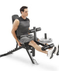 Man using Six Position Adjustable Utility Bench With Leg Developer And High Density Foam Padding for leg extensions, dark gray model