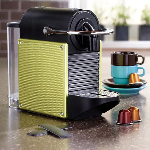 Compact yellow and black espresso machine with coffee cups and pods on a kitchen counter, showing modern design.