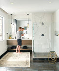 Bathroom with modern design featuring shower area, vanity, and a man using a mirror in a sleek, minimalist space.