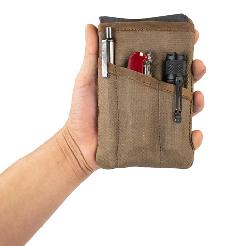 Hand holding a Slim Waxed Canvas EDC Pocket Pouch With Leather Accents, Compact Zippered Tool Case For Camping And Everyday Carry