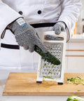 Chef using 3 Pairs Cut Resistant Gloves HDPE Food Grade Level C EN388 For Kitchen Prep with grater and cucumber on board.