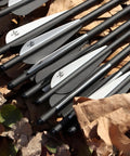 Close-up of 16-inch carbon crossbow arrows with black and white TPU vanes on leaves. Carbon Crossbow Arrows 16 Inch 12 Pack For Hunting And Target Practice.