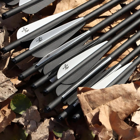 Close-up of 16-inch carbon crossbow arrows with black and white TPU vanes on leaves. Carbon Crossbow Arrows 16 Inch 12 Pack For Hunting And Target Practice.