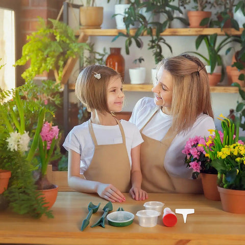 A mother and daughter using a Seven Piece Mini Seed Spreader Set With Handy Handheld Seed Sower Dispensers Dibber And Widger in a garden.