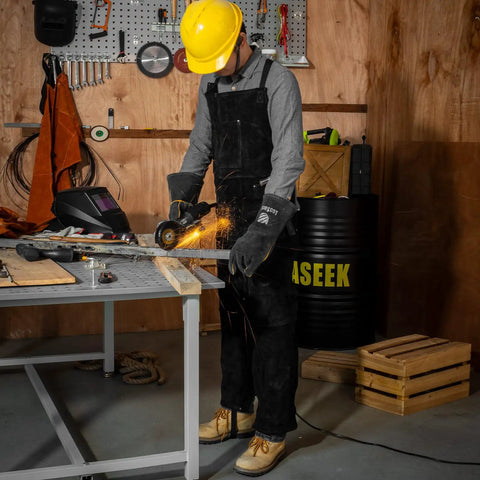 Person welding in shop wearing Pro Grade Heavy Duty Leather Welding Apron With Split Leg Design For Men And Women Cowhide Two Layer Fire Resistant Forge Apron Sparks Shield Heat Resistant Adjustable Straps Black and protective gear.